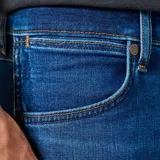 Jean Wrangler Larston de corte ajustado, color azul denim con lavado medio y costuras a tono.
