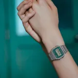 Reloj digital Casio modelo A158WEM-3DF con caja de 33mm y brazalete de malla de acero inoxidable. Presenta una esfera de color verde con pantalla digital, funciones de cronómetro, alarma y calendario automático.