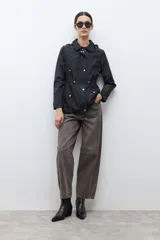 Campera impermeable color negro con capucha desmontable, cuello alto, cierre frontal con botones a presión y cordón ajustable en la cintura.