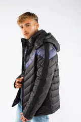 Campera puffer de nylon con relleno de guata, diseño capitoneado y capucha desmontable. Presenta un patrón de chevron en color azul sobre base negra, cierre frontal y bolsillos laterales con cierre.