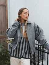 Campera gris con cierre frontal, cuello camisero y mangas largas con puños elásticos.