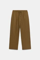Pantalón de tiro medio y pernera recta con textura, de color marrón. Cuenta con cintura elástica y cordón ajustable con abalorios decorativos.