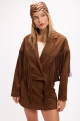 Chaqueta de efecto gamuza en color marrón, con solapas amplias, cierre frontal con botones y detalle de flecos largos en la parte delantera y trasera. Presenta una estructura definida y diseño de estilo western.