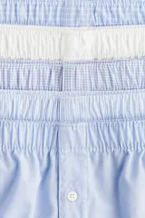 Pack de cinco calzoncillos tipo boxer de algodón, con cintura elástica y cierre frontal de botón. El set incluye modelos lisos y estampados en tonos azules y blanco.