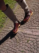 Botas altas de cuero marrón combinadas con gamuza blanca con estampado de vaca, forradas en cuero y con cierre de bronce.