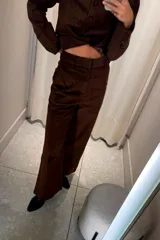 Pantalón de pana color marrón, de corte recto y tiro medio, con diseño de pierna ancha y cierre frontal.