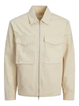 Chaqueta color crema con cuello camisero, cierre frontal con cremallera metálica, bolsillos de parche con solapa abotonada en el pecho y corte recto.