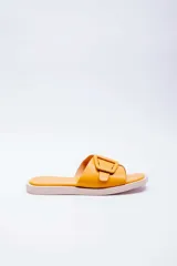 Sandalias planas color amarillo mostaza con tira ancha en el empeine decorada con una hebilla grande del mismo tono. Plantilla acolchada a tono y suela blanca.