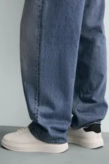 Zapatilla de cordones color blanco hueso, con parte superior lisa y suela de plataforma gruesa. Presenta un detalle de pieza negra en el talón.