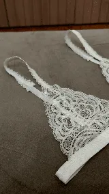 Sostén tipo bralette negro de encaje elastizado, con diseño triangular y breteles con detalle de encaje.