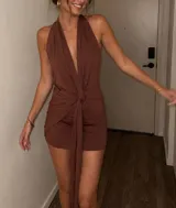 Vestido corto marrón con escote halter cruzado y detalle de nudo frontal con tiras colgantes.