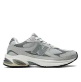Championes urbanos New Balance modelo 2010, color gris con detalles en blanco y negro. Confeccionados con una combinación de malla transpirable, nobuk y materiales sintéticos. Presentan entresuela con tecnología ABZORB para absorción de impactos, inserciones SBS en talón y antepié, y refuerzo TPU Stability Web en la zona media.