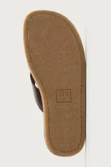 Sandalia de cuero marrón con diseño de tiras en el empeine y suela plana.