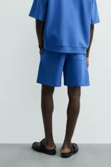 Bermuda de algodón color beige claro, corte relajado (relaxed fit), con cintura elástica ajustable mediante cordón y bolsillos laterales y trasero de plastrón.