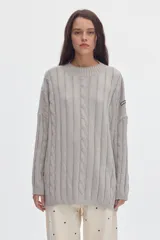 Buzo negro de tejido de ochos, con cuello redondo y diseño oversized de corte largo y amplio con tajos laterales.