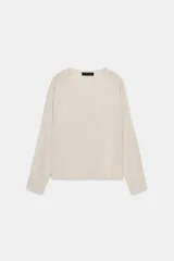 Jersey de punto color gris claro con hilo metalizado, de cuello redondo y manga larga. Bajo recto con aberturas laterales.