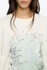 Buzo cropped de corte recto, color blanco hueso, con cuello redondo y mangas largas amplias. Presenta un estampado frontal de estilo ilustrativo con un paisaje nocturno, árboles, cisnes volando y una luna creciente, con tonos verde agua y naranja para las estrellas.