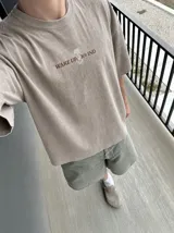 Remera oversize de color marrón topo con efecto acid wash, cuello redondo y manga corta. Cuenta con un pequeño estampado gráfico frontal con el texto 'WAKE UP IND' y una calavera.