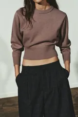 Jersey de punto liso con diseño cropped, cuello redondo y manga larga. Presenta acabados en rib en cuello, puños y bajo.