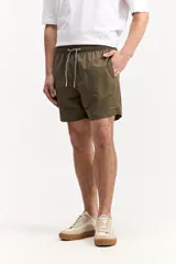 Short de baño verde militar con cintura elástica, cordón ajustable bicolor y bolsillos laterales. Cuenta con pequeños bordados de la marca en la pierna.