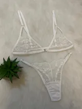 Conjunto de lencería compuesto por un bralette de encaje con cierre frontal y una tanga regulable con corte en V, ambos en color blanco.