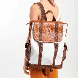 Mochila de cuero vacuno color blanco, whisky y marrón, con textura tipo piel de cocodrilo. Tiene un bolsillo con broche a presión a cada costado y un bolsillo con cierre en la parte trasera. El interior está forrado y contiene un bolsillo con cierre y otro pequeño para el celular.