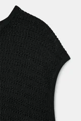 Top de punto negro con cuello redondo, manga sisa y bajo asimétrico.