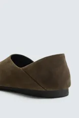 Zapato tipo mocasín sin cordones fabricado en piel con acabado serraje. Presenta talón plegable, horma redonda y suela de goma Vibram.