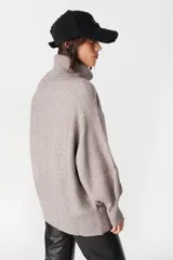 Sweater de punto con textura acanalada, cuello alto tipo polerón, mangas largas con diseño abuchonado y puños anchos.
