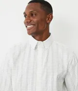 Camisa de corte comfort confeccionada en algodón texturizado con diseño de rayas horizontales finas. Presenta cuello camisero, manga larga con puños abotonados y cierre frontal con botones.