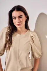 Remera de algodón negro con mangas cortas abullonadas, cuello redondo y costura central frontal.