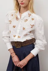 Camisa blanca de manga corta con cuello mao y volados, botones frontales y bordados de hojas y flores en color dorado.