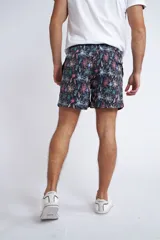 Short de baño con cintura elástica y cordón ajustable, confeccionado en tela ligera de secado rápido. Presenta un estampado botánico integral en tonos amarillos, blancos y azules, con dos bolsillos delanteros y uno posterior.