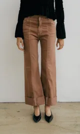 Pantalón de denim color marrón, de corte ancho y tiro alto, con costuras contrastantes claras y dobladillo ancho en el ruedo.