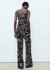 Pantalón de tiro medio confeccionado en mezcla de lino y viscosa, con diseño recto, bolsillos laterales, trabillas y cierre de botón y cremallera. Presenta un estampado de flores y hojas de estilo lineal en contraste.