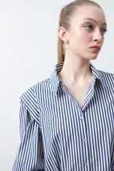 Camisa a rayas azules y blancas de manga larga, con cuello clásico y puños abotonados. Presenta un diseño entallado en la cintura.