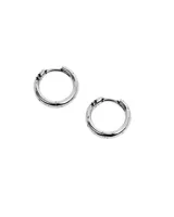 Par de aros tipo argolla (huggie) de metal plateado con acabado envejecido. Presentan un diseño liso con pequeñas estrellas grabadas alrededor del borde.