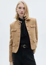 Chaqueta de corte recto confeccionada en tejido tweed con mezcla de lana. Presenta cuello de tira, cierre frontal con botones, manga larga y cuatro bolsillos delanteros con solapa y botón. Incluye forro interior.