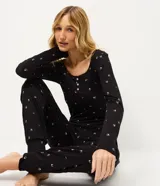 Pijama de dos piezas confeccionado en tejido rib acanalado con estampado floral. Incluye una blusa de manga larga con cuello redondo y cierre frontal de botones, y un pantalón largo con cintura elástica.