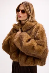 Campera corta de pelo sintético en color marrón, con diseño de volumen protagonista, cuello alto y cierre frontal.