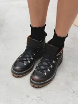 Borcego de cuero negro con cordones y suela track color caramelo.