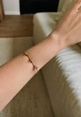 Pulsera dorada de bronce con cruces pequeñas.