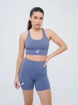 Top deportivo color gris azulado con diseño de espalda natación y el escudo del Club Nacional de Football en el centro.