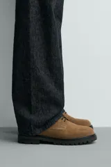 Zapato de cordones tipo derby en piel con acabado serraje color verde militar. Horma redonda y suela track negra a contraste.