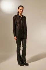Camisa negra traslúcida de lyocell con cuello clásico, cierre frontal con botones y detalles de strass en cuello, botones y puños.