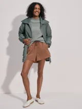 Campera larga color verde con cuello acanalado, cierre de doble sentido, bolsillos de parche grandes, cintura interior ajustable y puños con borde con volados.