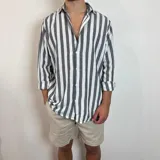 Camisa de lino de corte oversize con diseño de rayas verticales en tonos blanco y tostado, manga larga y cierre frontal con botones.