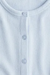 Saco de punto con textura tipo waffle, color celeste, de ajuste entallado, cuello redondo y cierre frontal con botones.