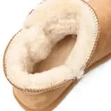 Bota corta tipo australiana color habano, con acabado gamuzado y forro interno de piel sintética. Presenta un detalle de cierre lateral con botón de madera y elástico.