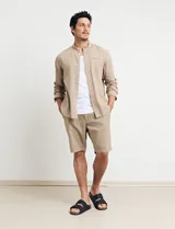 Camisa de cuello mao y manga larga, confeccionada en una mezcla de lino y algodón. Presenta un diseño de corte recto con botones en tono natural y un bolsillo pequeño en el pecho.